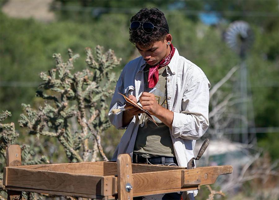 Field student Demitri DeLeon records information about artifacts recovered in the screen. (Photo by Tom Connelly)